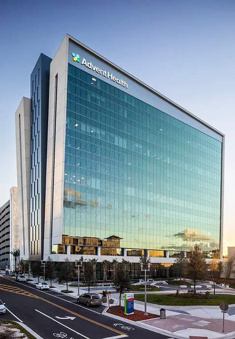 Glass curtain wall facade of AdventHealth Innovation Tower, a 12-story medical office building beside I-4 in Orlando, Florida