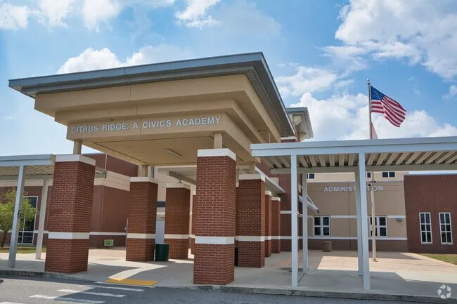 Main entrance canopy of Citrus Ridge: A Civics Academy in Davenport, Florida, with brick columns, the school name sign and an American flag