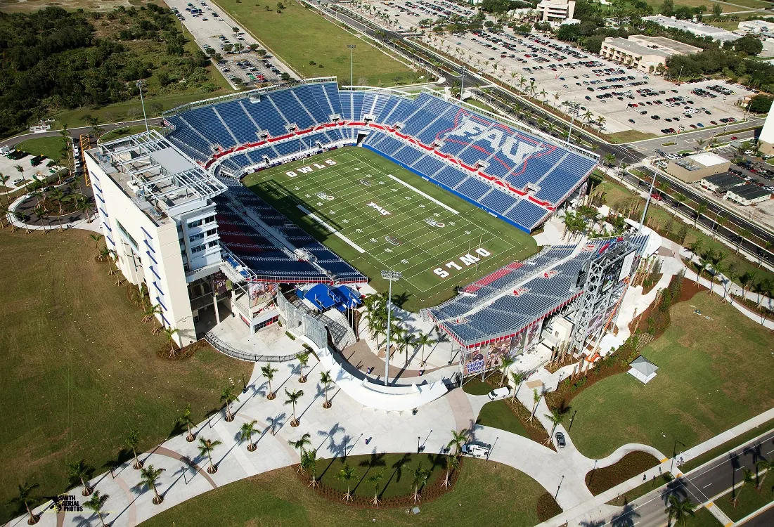 Aerial view of FAU Stadium on the Florida Atlantic University campus in Boca Raton, Florida, with blue and red seating and the multi-level suite building
