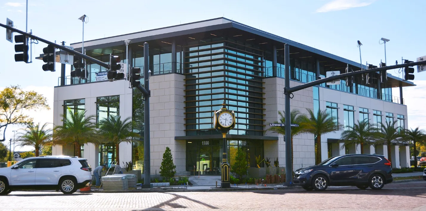 Three-story McCraney office and retail building on Orange Avenue in Winter Park, Florida, with a stone facade, glass entry and street clock