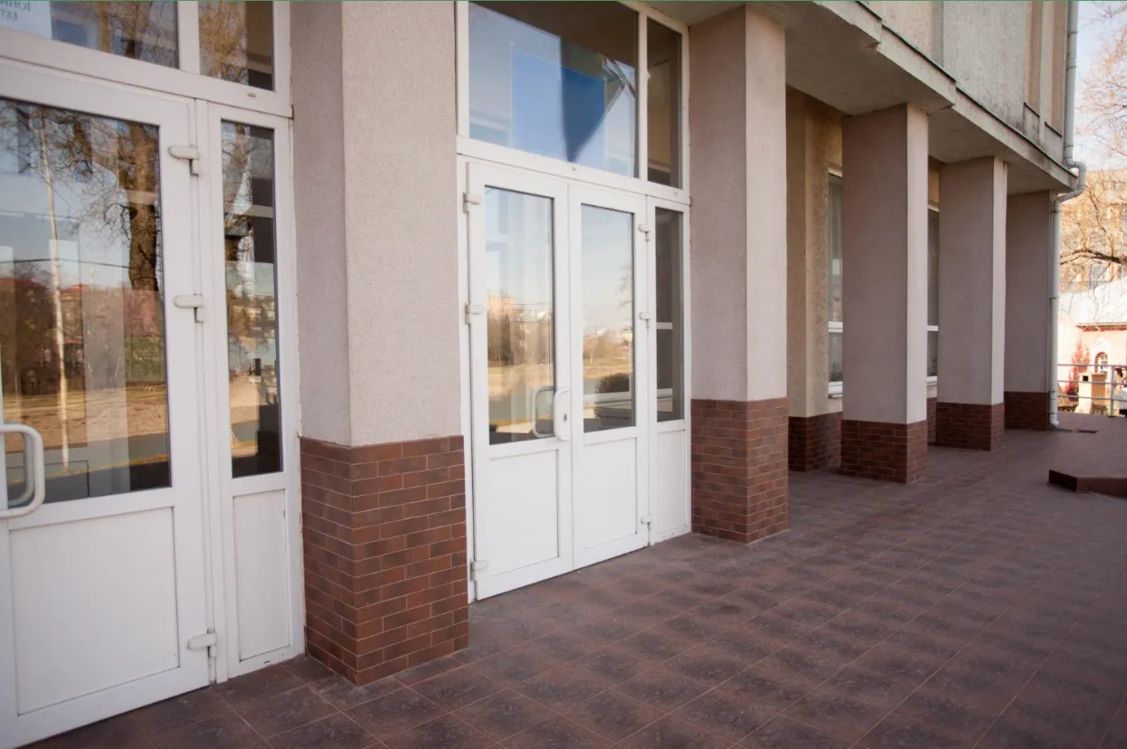 White commercial entry doors with glass lites and transoms along a brick and stucco building exterior