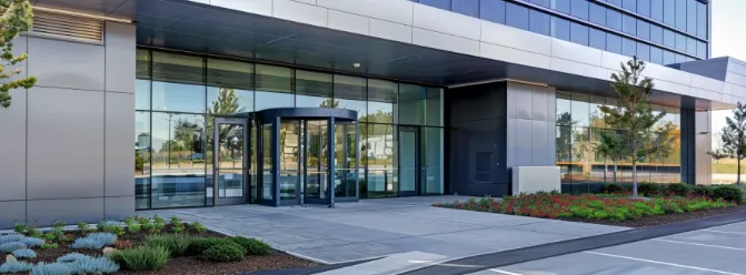 Modern commercial building entrance with a revolving door and floor-to-ceiling glass